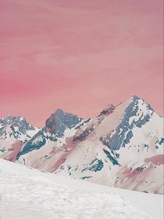 a man riding skis down the side of a snow covered slope under a pink sky