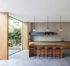 an open kitchen with wooden cabinets and stools next to the counter top, along with large sliding glass doors leading outside