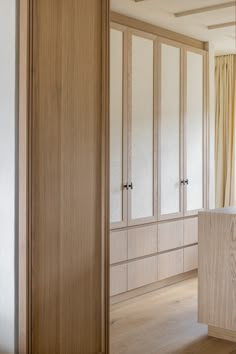 an empty room with white walls and wooden cabinets in the center, along with wood flooring