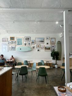 two people sitting at tables in a room with pictures on the wall