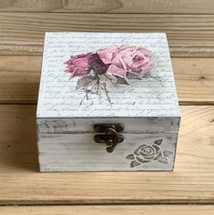 a wooden box sitting on top of a wooden floor covered in writing and pink roses