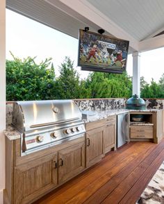 an outdoor kitchen with wood floors and grilling area on the side of the house