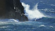 a large wave crashes into the side of a rocky cliff in the middle of the ocean