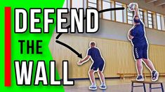 two men are playing volleyball in an indoor court with the words defend the wall above them