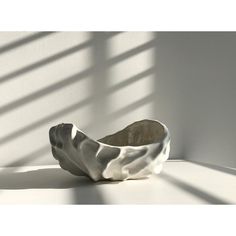 a white bowl sitting on top of a table next to a window with long shadows