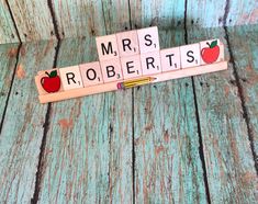 scrabble tiles spelling the word mrs roberts with an apple and pencil on top