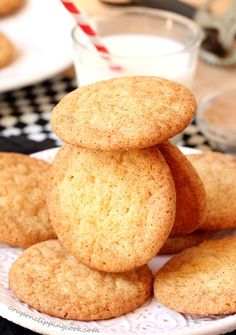 cookies stacked on top of each other on a plate with a glass of milk in the background