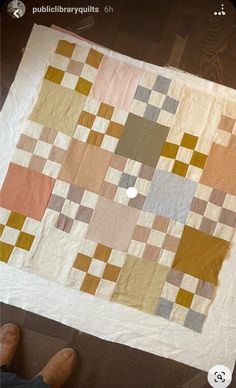 a person sitting on the floor next to a large piece of fabric that has been made into a quilt