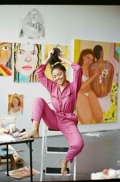 a woman sitting on top of a chair in front of paintings