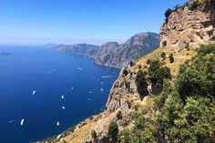 boats are floating on the water near cliffs