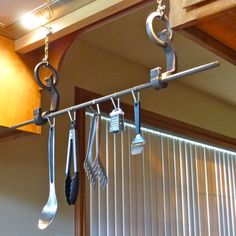 kitchen utensils hanging from the ceiling in front of blinds