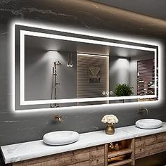 a bathroom with two sinks and a large mirror on the wall above it that is illuminated by lights