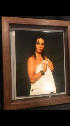 a framed photograph of a woman in white dress holding a knife and looking at the camera