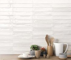 kitchen utensils and coffee cups on a wooden table with white tiles in the background