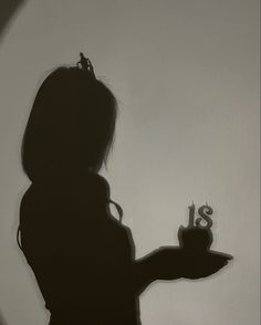 the silhouette of a woman holding a cake with candles in her hand and number thirteen on it