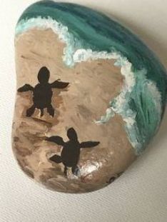 a painted rock with two children playing on the beach