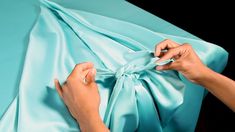 a woman is tying a blue satin fabric