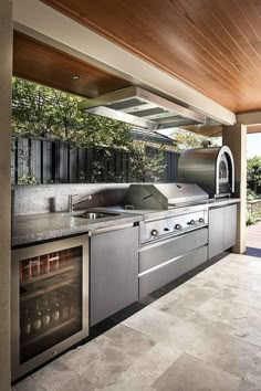 an outdoor kitchen with stainless steel appliances and wood ceilinging is seen in this image