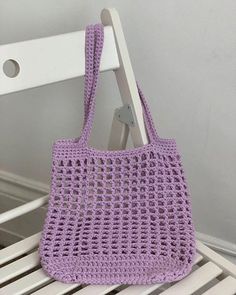 a purple crocheted bag sitting on top of a white chair