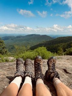 two people sitting on top of a mountain with their legs crossed