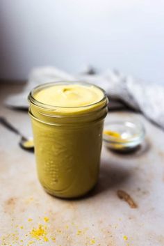 a glass jar filled with yellow liquid sitting on top of a counter next to two spoons