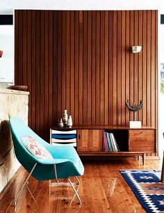 a blue chair sitting on top of a hard wood floor next to a book shelf