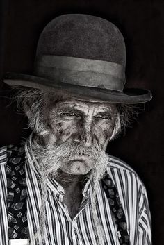 an old man wearing a hat and striped shirt