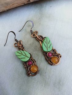 Cute bohemian leaf Earrings, petite on. Natural Tropez gemstone yellow, with Fuschia pink bead, green ceramic leave wire wrapped in bronze wire makes these earrings very unique on. The earrings are half an inch wide, length from bronze hook to bottom earring dangles 2 inches drop. The earrings come gift wrapped in a nice box with a card if you would like a message put on the card please let me no on checkout. Bohemian Leaf-shaped Brass Jewelry, Bohemian Brass Leaf Jewelry, Green Copper Wire Earrings Gift, Bohemian Hand-wrapped Copper Wire Earrings, Bohemian Hand Wrapped Copper Wire Earrings, Bohemian Jewelry With Copper Wire And Matching Earrings, Earthy Green Wire Wrapped Jewelry, Handmade Leaf-shaped Metal Jewelry, Bohemian Leaf-shaped Metal Jewelry