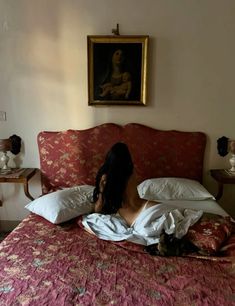 a woman laying on top of a bed next to a cat