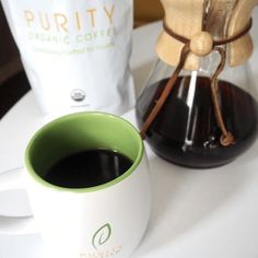 a cup of coffee sitting on top of a table next to a bag of coffee