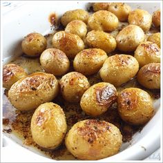 cooked potatoes in a white dish with seasoning sprinkled on the top and bottom