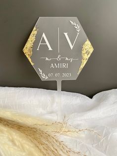 a clear acrylic sign with gold foiling on it sitting on a bed