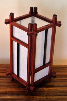 a wooden table lamp sitting on top of a hard wood floor next to a wall