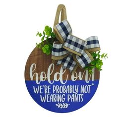 a wooden sign with a bow hanging from it's side that says, hold on we're probably not wearing pants