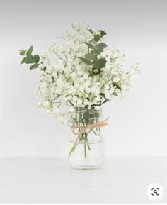 a vase filled with white flowers and greenery