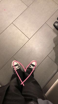 someone is standing on the floor with their feet crossed and holding a pink heart in front of them