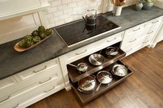 pots and pans are stacked on the bottom shelf of a stove in a kitchen