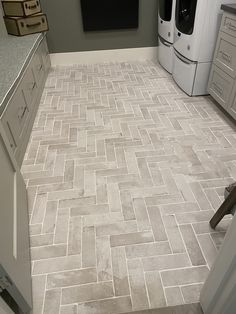 a kitchen with white cabinets and gray tile flooring in the center, next to a washer and dryer