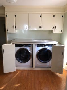 a washer and dryer are in the middle of a room with white cabinets