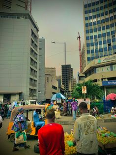 some people are walking around in the street with fruit and vegetables on display at an open air market