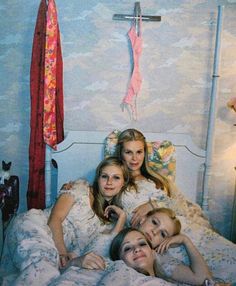 three young women laying in bed with their arms around each other