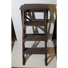 a wooden shelf sitting on top of a white floor next to a shadow cast wall