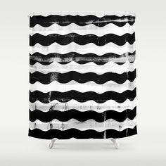 a black and white shower curtain with wavy lines on the bottom, against a gray background