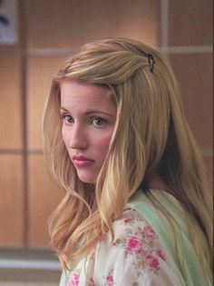 a woman with long blonde hair standing in front of a kitchen counter and looking off to the side