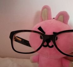 a pink stuffed animal with glasses on top of it's head and eyeglasses in the shape of a rabbit