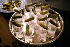 there are many glasses with pickles in them