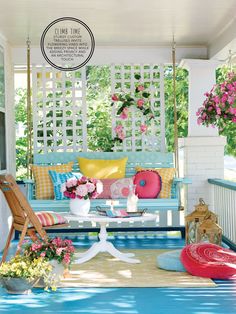 a porch swing with pillows and flowers on the back ground, in front of a white pergolated wall