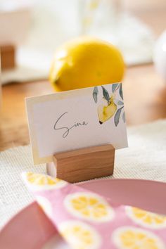 a place card holder sitting on top of a table next to a plate with lemons