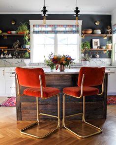 two orange chairs sitting on top of a wooden counter in front of a kitchen window