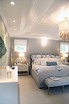 a bedroom with a large bed and chandelier hanging from it's ceiling